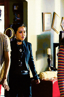 a woman in a black jacket stands in a living room
