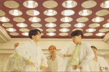 a group of young men are dancing in front of a ceiling with circles of lights