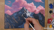 a person is painting a mountain with pink clouds and the words made in animatica