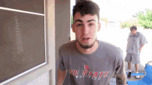 a young man wearing a gray nc state wolfpack shirt