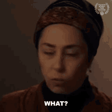 a woman wearing a head scarf and a hat is asking what .