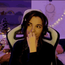 a woman wearing headphones is sitting in a gaming chair and covering her nose