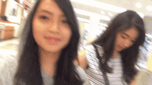 two young women are standing next to each other in a store .
