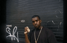 a man stands in front of a wall with graffiti on it that says sr