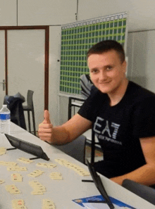 a man wearing a black shirt that says ea7 is giving a thumbs up