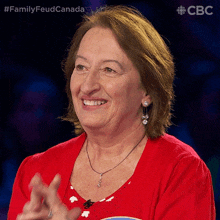 a woman wearing a red shirt and earrings is smiling and clapping in front of a cbs logo