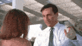 a man in a suit and tie is talking to a woman in a bikini .