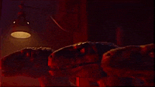 two dinosaurs are laying on a bed in a dark room with a lamp hanging from the ceiling .