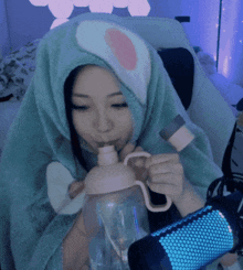a woman wearing a bunny hood is drinking from a bottle