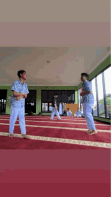 two men are standing on a carpet in a mosque