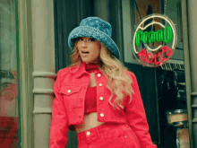 a woman in a red jacket and hat stands in front of a sign that says coca cola rolls