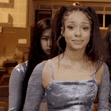 a girl with pigtails looks at the camera while another girl looks on
