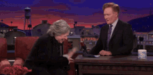 a woman is laughing while sitting next to a man on a stage .