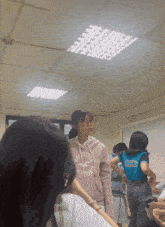 a girl in a pink hollister hoodie stands in a classroom