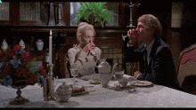 a man and a woman are sitting at a table drinking tea