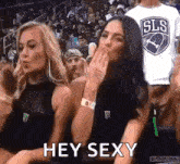 two cheerleaders are blowing kisses at a basketball game and one of them is wearing a sls shirt