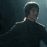 a man in a black shirt smiles in the dark