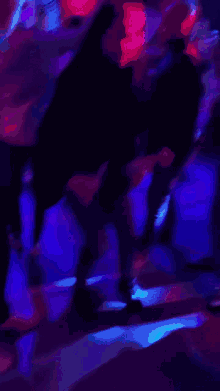 a group of people are dancing in a dark room with a purple light behind them that says bud light
