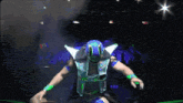 a wrestler in a blue and green outfit is holding a cowboy hat in his hand