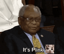 a man in a suit and tie is sitting in front of a cat and says it 's blink .