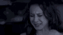 a woman is sitting in a car with her eyes closed and her hand on her head .