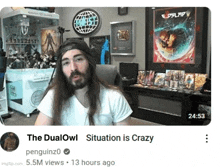 a man with long hair and a beard is sitting in front of a screen that says " the dualowl situation is crazy "