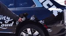 a person is pointing at a black car with n3 written on it