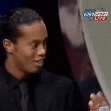 a man in a suit and tie is holding a trophy in front of a eurosport live screen .