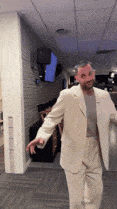a man in a white suit stands in a hallway