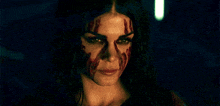 a woman with blood on her face is looking at the camera .