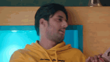 a man wearing a yellow hoodie with the letter t on the front
