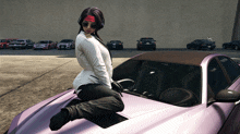 a woman kneeling on the hood of a purple car