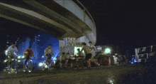 three men are riding bicycles down a street with a building in the background that says ' l ' on it