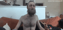 a shirtless man with a beard is sitting on a couch with powerchat.live/potato69 in the corner