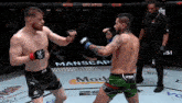 two men are fighting in a ring with a manscap advertisement on the wall behind them