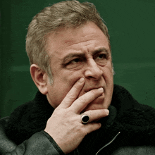 a man wearing a black jacket and a ring on his left hand