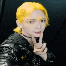 a person with yellow hair is giving the peace sign