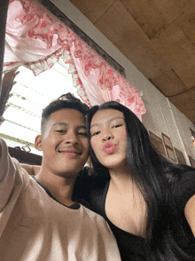 a man and a woman pose for a picture in front of a pink curtain