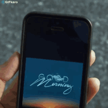 a person is holding a smart phone with the words good morning on the screen