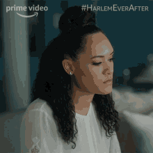 a woman in a white shirt is sitting in front of a sign that says harlem ever after