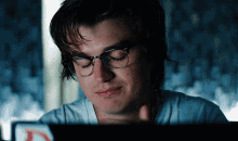 a man wearing glasses and a white shirt is looking at a laptop screen