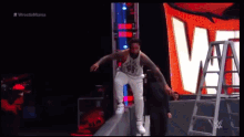 a wrestler is jumping over a ladder during a wrestling match
