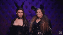 two women are standing next to each other wearing bunny ears and looking at each other .