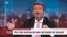 a man in a suit and pink tie is talking on a television screen