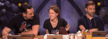 a group of people are sitting at a table and one of them is wearing a shirt that says ' mighty ' on it