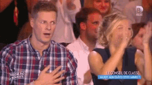 a man in a plaid shirt is sitting in a crowd .
