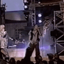 a man is singing into a microphone on a stage in front of a crowd of people .