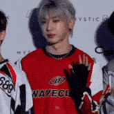 a man wearing a red and white wavecl jersey waves his hand