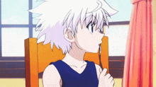 a young boy with white hair is sitting in a chair holding a pair of glasses .