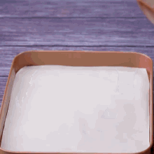 a bowl of chocolate sauce is being poured into a pan of wax paper